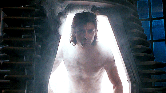 A gif of a tall nude man (Jeff Goldblum) with long hair exiting a pod-type structure.