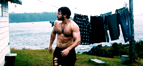 A GIF of a shirtless man wearing torn pants sneaking through a yard.