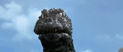 A GIF of Godzilla glaring at the camera and wagging a finger in warning.