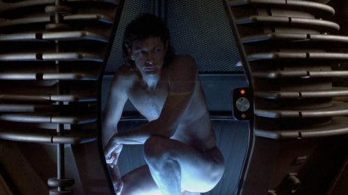 A still from 'The Fly'. A naked man crouches down in a scientific teleporter.