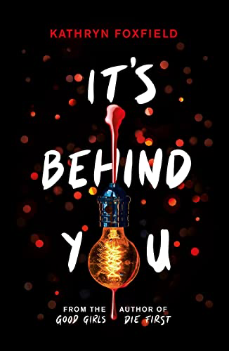 Book cover for "It's Behind You" by Kathryn Foxfield with an image of a glowing light bulb dripping blood against a dark background with red lights.