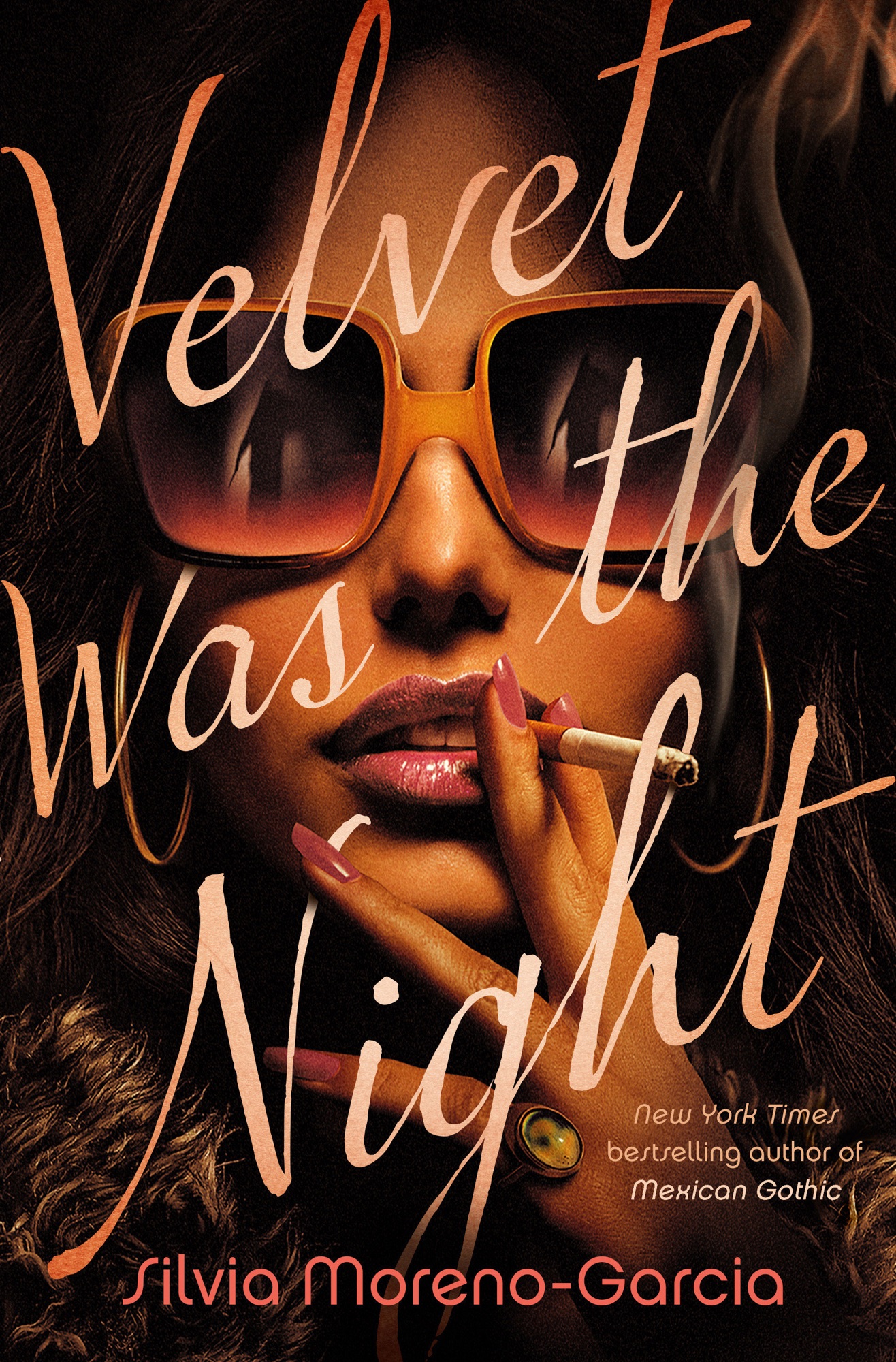 Book cover featuring the title "Velvet Was the Night", and the author's name "Silvia Moreno-Garcia" in stylized orange font. The background is dark with what appears to be textured hair and a partial glimpse of a cat's eye at the bottom right corner. There is an overlay with the words "New York Times bestselling author of Mexican Gothic."